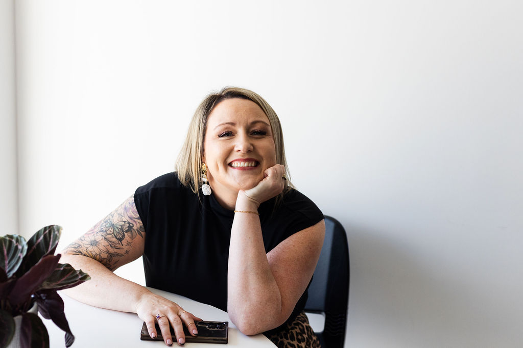 Rose smiling with her chin resting on her hand at a white table