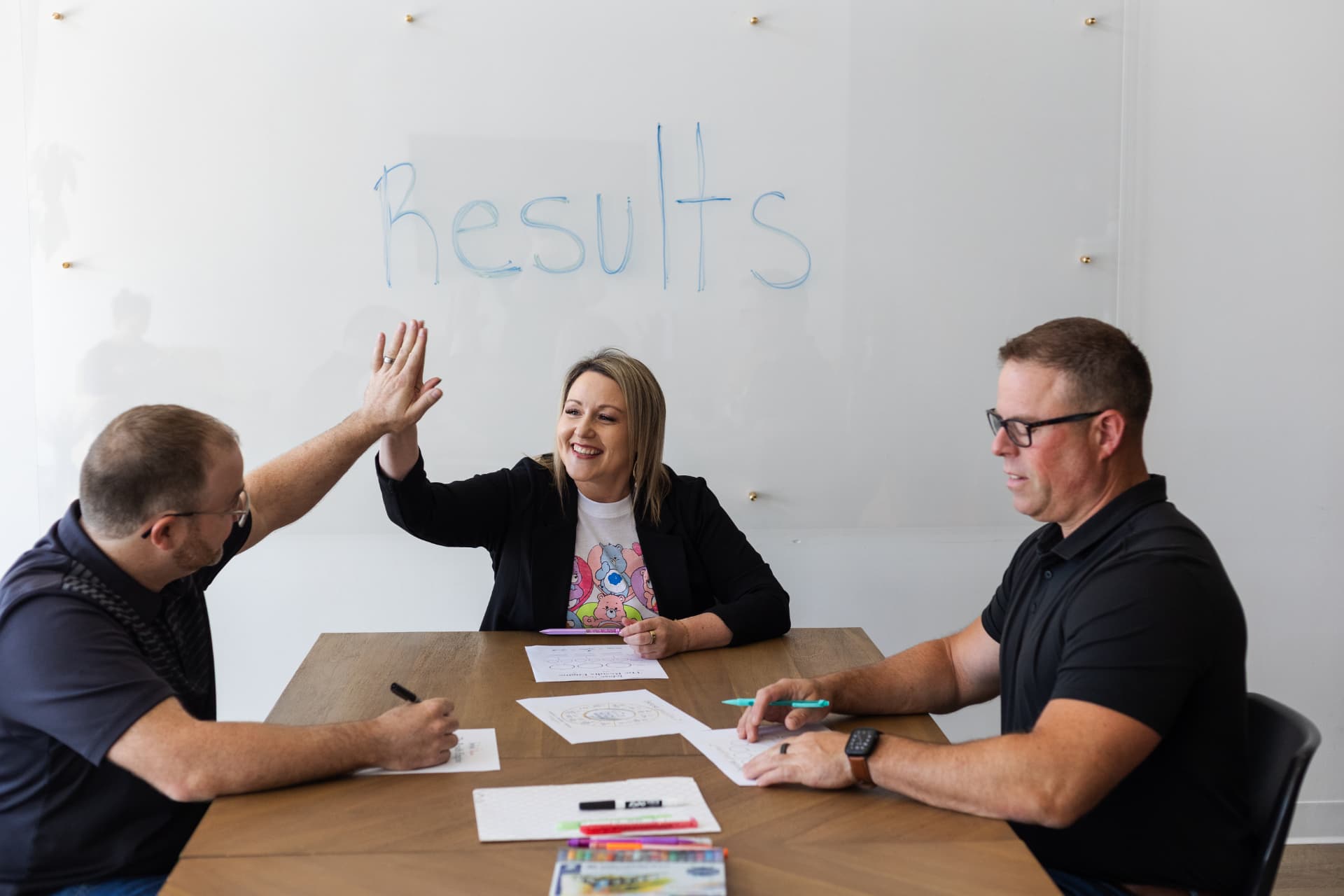 Rose high-fiving a client across the table while mapping The Results Engine